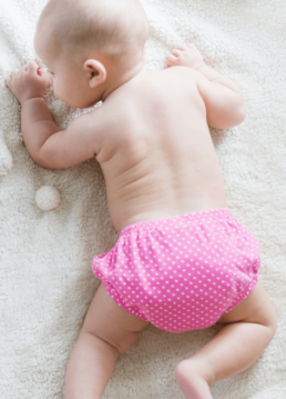 Bébé sur le ventre avec une couche rose lavable