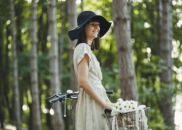 Femme souriante avec un chapeau à côté de son vélo fleuri