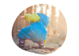Enfant en tenue bleu et verte ramasse un bout de bois dans la nature